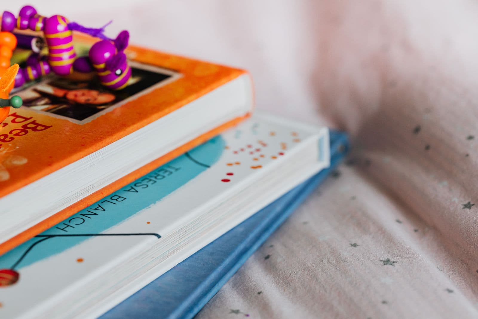 Zwei Kinderbücher liegen aufeinander auf einer hellen Decke.