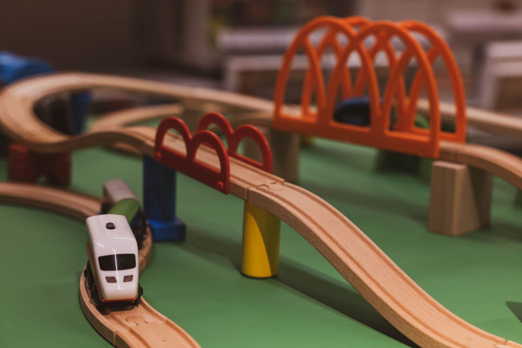 Eine Holzeisenbahn mit Brücken auf einer grünen Spielplatte.
